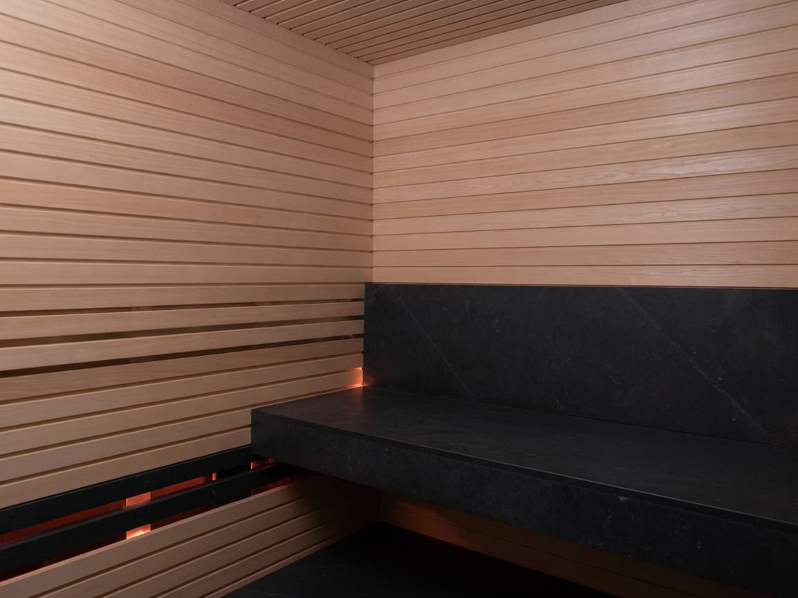 Hemlock sauna with a black stone bench and a low ember glow