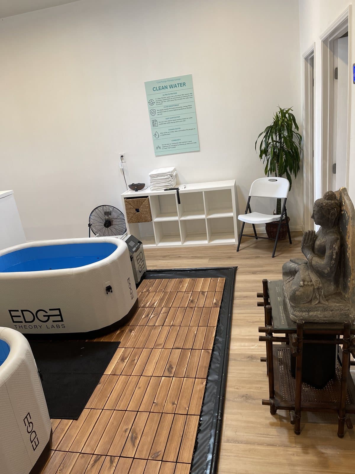 A finished plunge room with a single steel-framed tub, wood decking and a stone statue